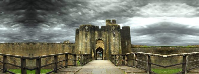 Trip Voucher Reisetipps - Caerphilly Castle - ein Bollwerk aus dem 13. Jahrhundert in Wales, Vereinigtes Königreich. Mit einem aufsehenerregenden Turm, der schiefer ist wie der Schiefe Turm zu Pisa. Wie jede Burg mit Prestige, hat sie auch einen Geist, „The Green Lady“ spukt in den Gemächern, wo ihr Geliebter den Tod fand. Wo man in Wales oft – und nicht ohne Grund – das Gefühl hat, dass ein Schloss ziemlich gleich ist, ist Caerphilly Castle bei Cardiff eine sehr willkommene Abwechslung. Die Burg ist nicht nur deutlich größer, sondern auch älter als die Burgen, die später von Edward I. als Ring um Snowdonia gebaut wurden.